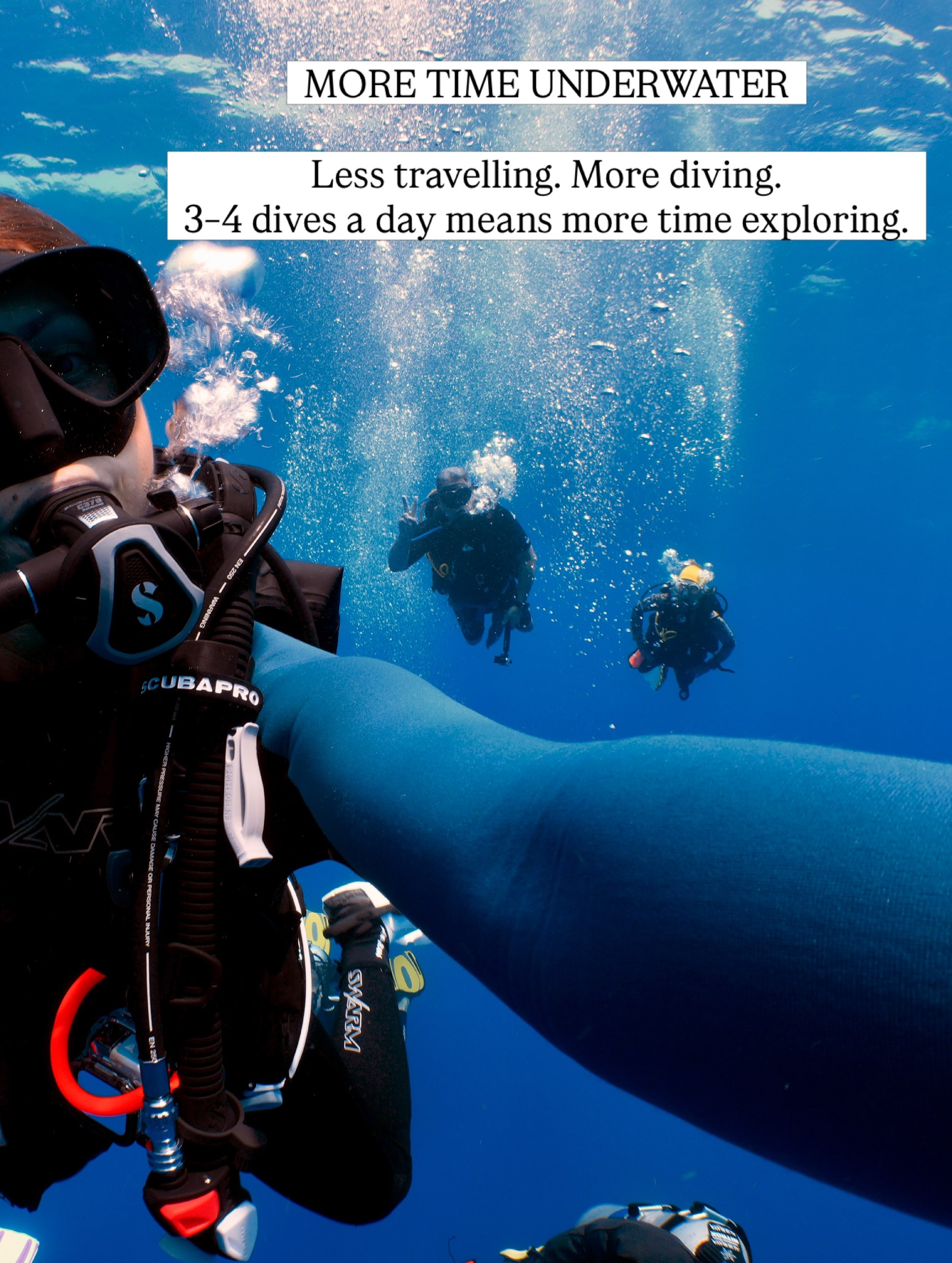 Divers descending together in blue water with sunlight above them