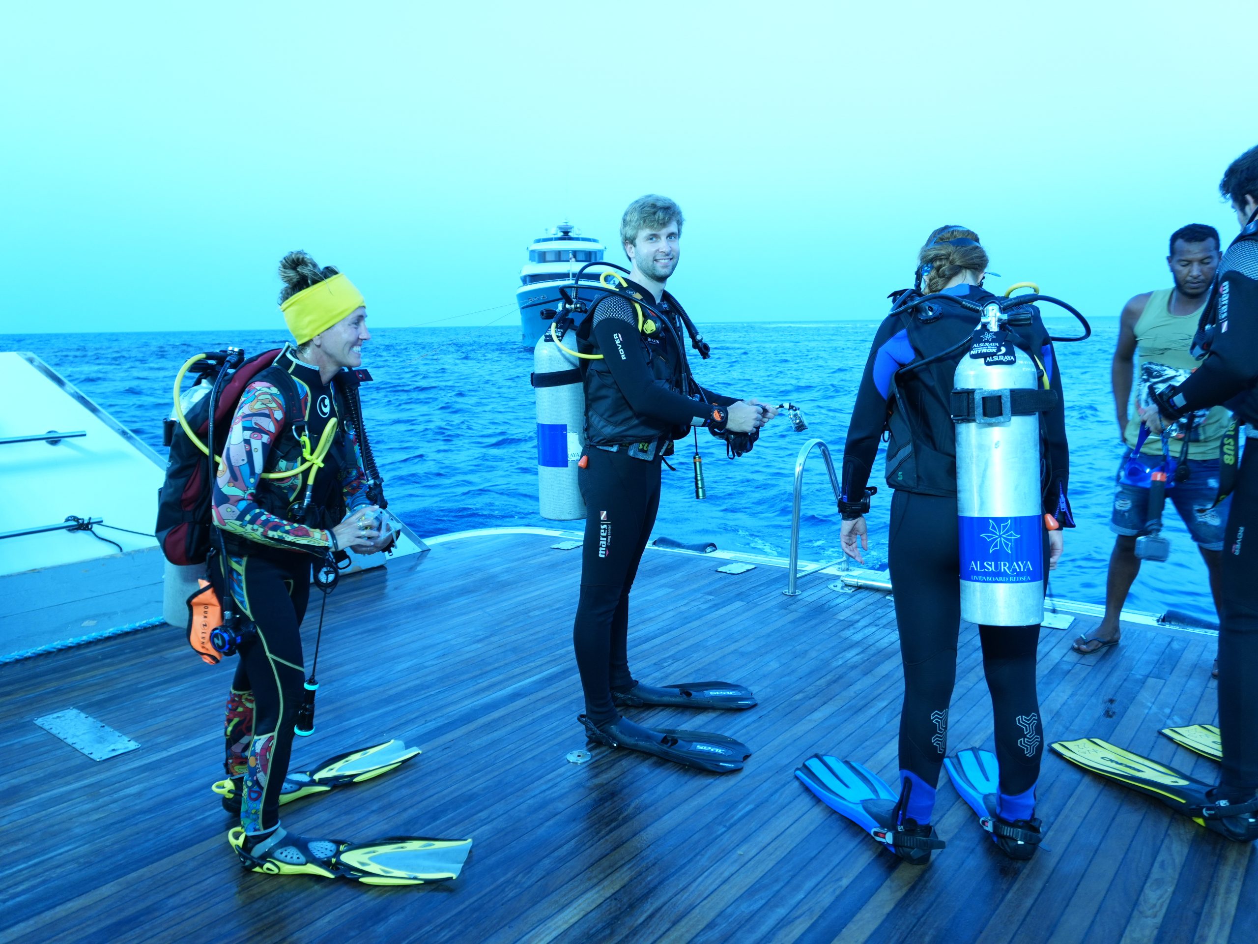 Divers checking equipment and preparing to enter the water from the deck of a Red Sea liveaboard