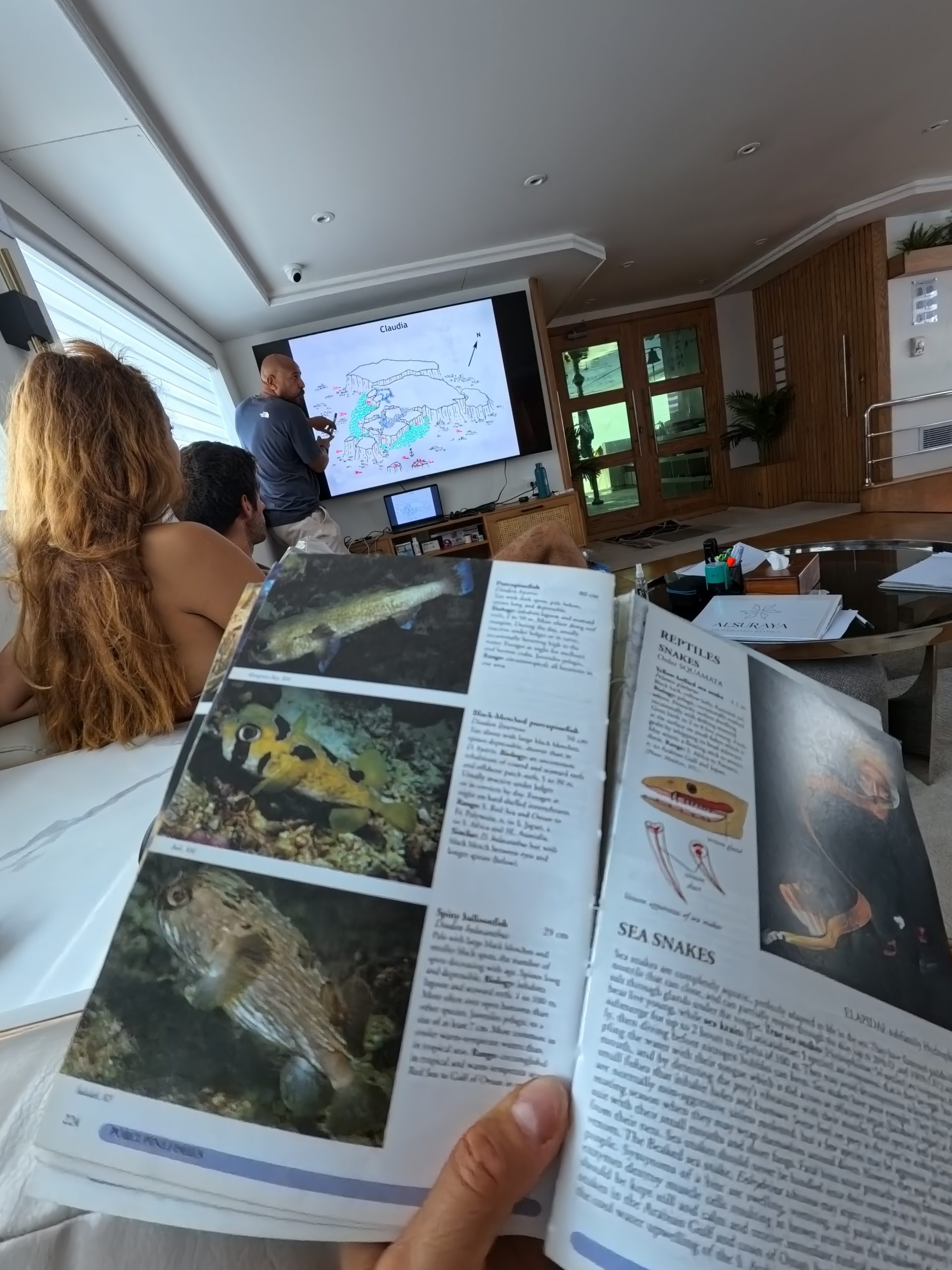 Reef dive briefing with a fish identification book aboard a liveaboard, Egypt