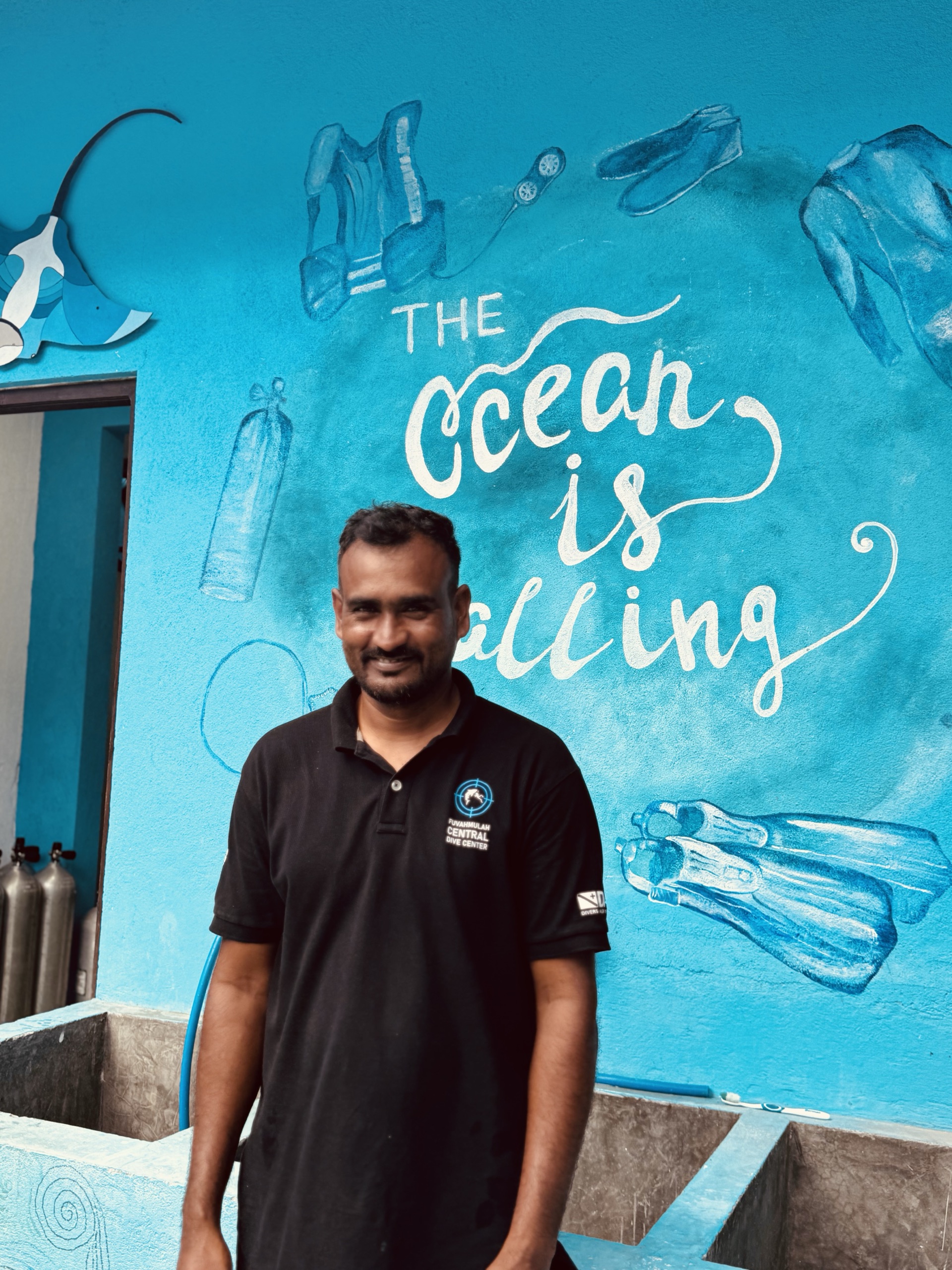 Fuvahmulah Central Dive Center crew member in front of 'The ocean is calling' mural