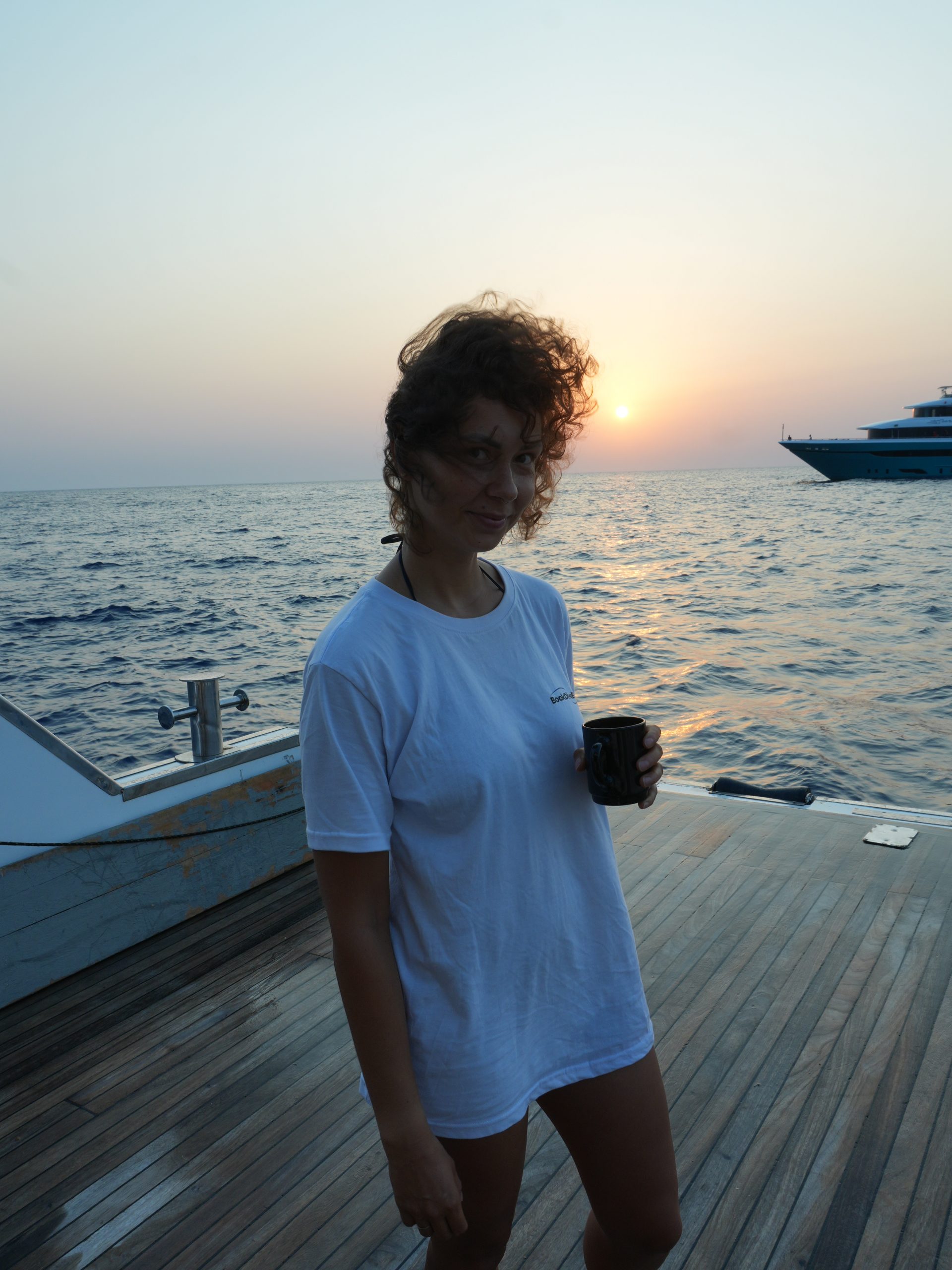 Guest with a mug on a Red Sea liveaboard deck at sunset, Egypt