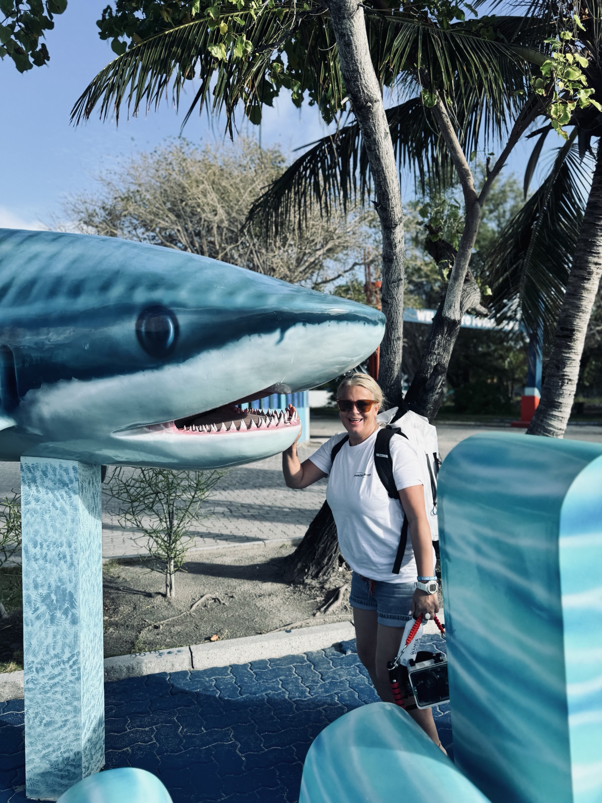 Sarah smiling next to a shark statue in Fuvahmulah, Maldives