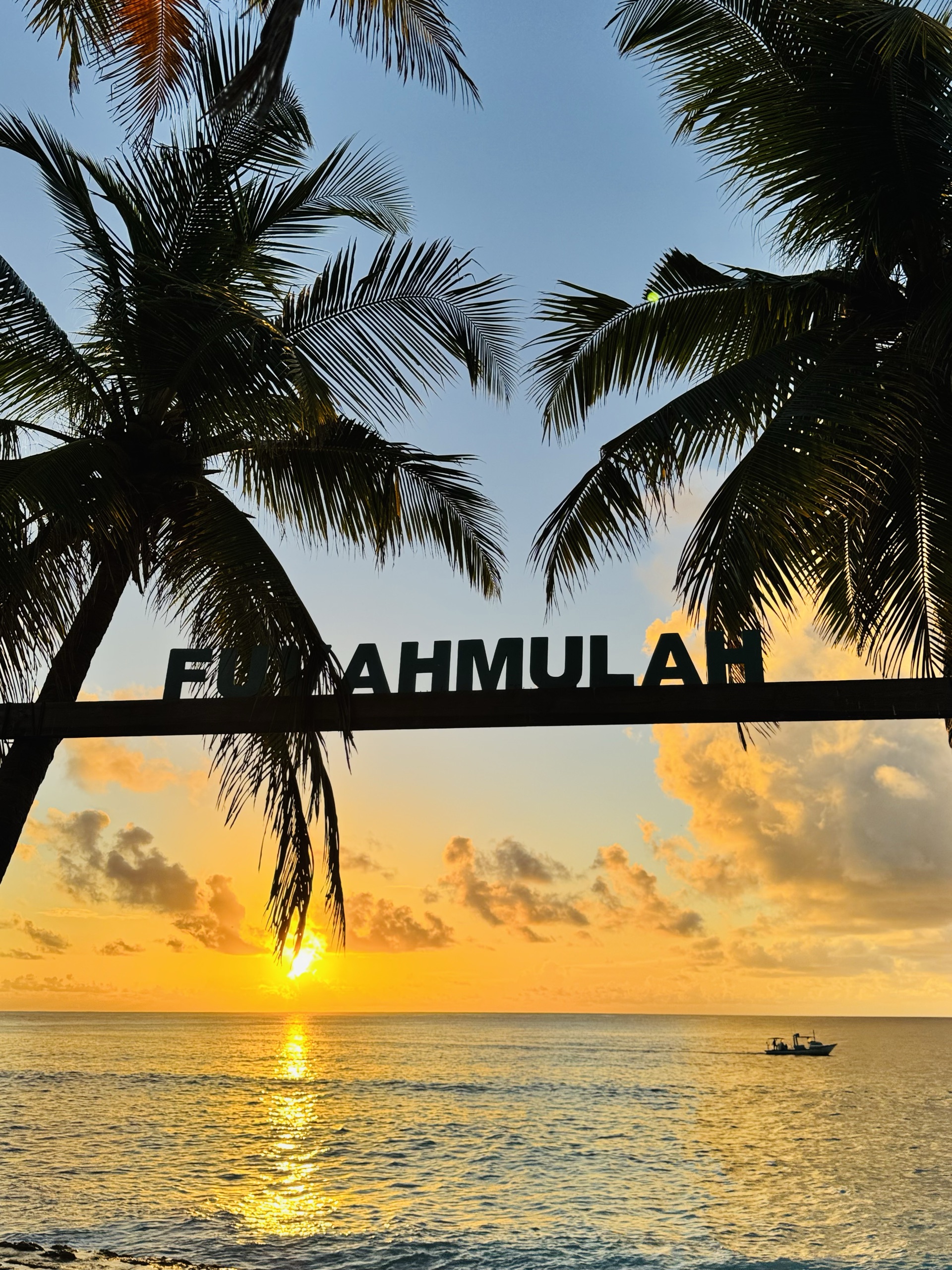 Sunset behind the Fuvahmulah sign and palm trees, Maldives