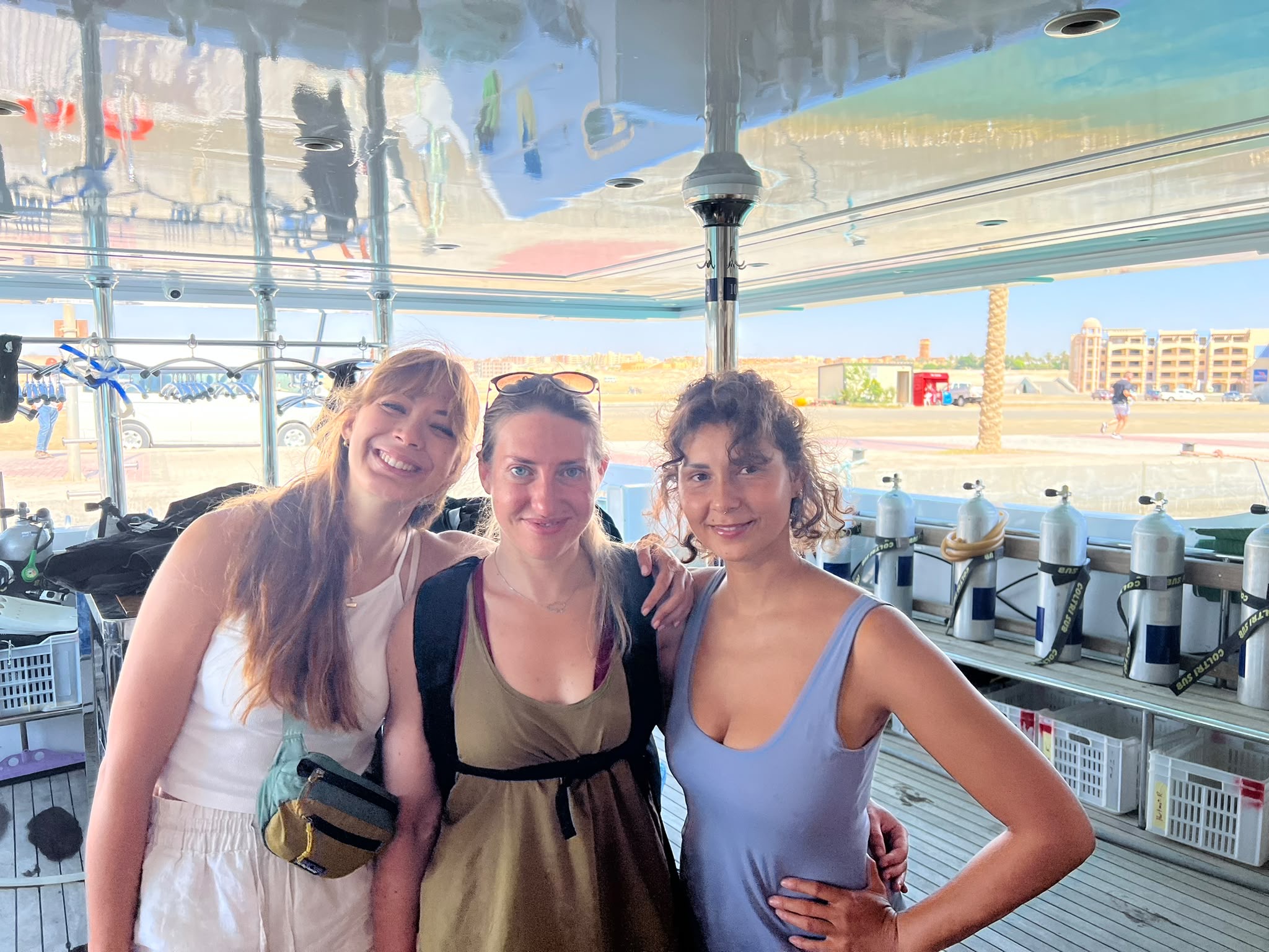 Three friends smiling on a liveaboard dive deck, Egypt